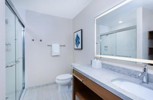 a bathroom with a toilet and a sink and a mirror at Candlewood Suites Erlanger - South Cincinnati by IHG in Erlanger