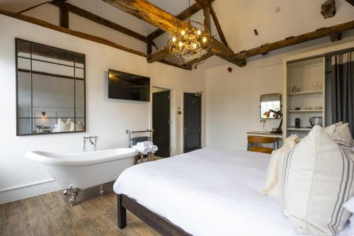 a bedroom with a bed and a bath tub and a sink at Tavern Townhouse in Henley on Thames