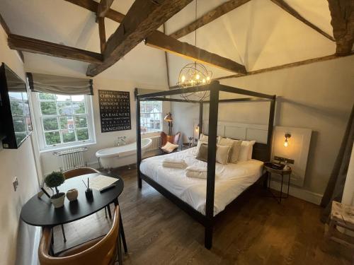 a bedroom with a canopy bed and a bath tub at Tavern Townhouse in Henley on Thames