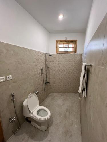a bathroom with a toilet and a window at ISLE OF HIGHLAND TOURS Guest House in Gilgit