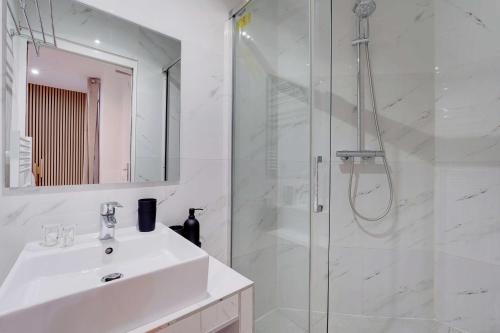 une salle de bain blanche avec un lavabo et une douche dans l'établissement Charming studio -2P- Canal Saint-Martin, à Paris