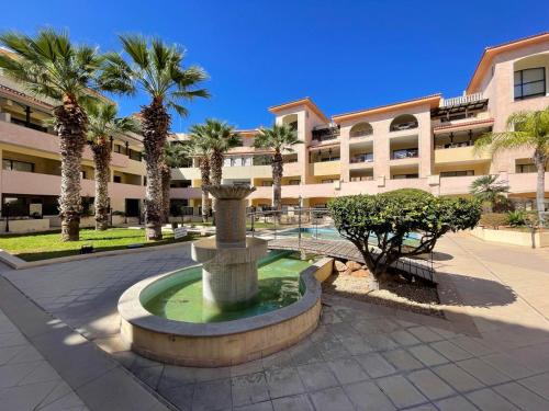 a fountain in front of a building with palm trees at Queens gardens in Paphos