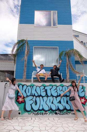 three people are standing in front of a wall with graffiti at HOMIE TERRACE Funakata in Tateyama