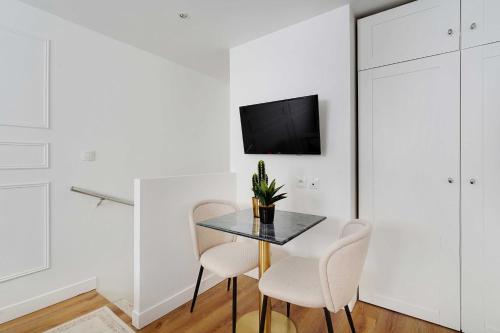 une salle à manger avec une table noire et des chaises blanches dans l'établissement Modern studio - 2P - Canal Saint Martin, à Paris