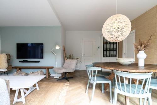 una sala de estar con una mesa y sillas en Hello Zeeland - Vakantiewoning Beach Lodge Zilt, en Biggekerke