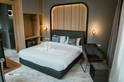 a bedroom with a large bed and a chair at Blooming resort buriram บลูมมิ่ง รีสอร์ท บุรีรัมย์ in Ban Makha