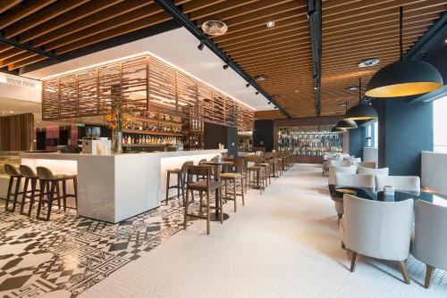 a restaurant with a bar with stools and chairs at INNSiDE by Meliá Zhengzhou in Zhengzhou