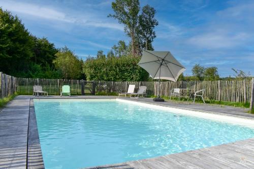 - une piscine avec un parasol et des chaises dans l'établissement La Chaumière du Vallon -Piscine- Pont-l'Évêque 8P, à Vieux-Bourg