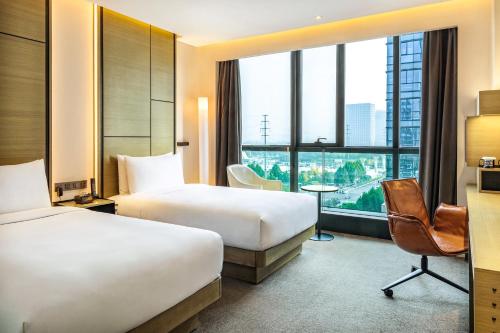 a hotel room with two beds and a large window at INNSiDE by Meliá Zhengzhou in Zhengzhou