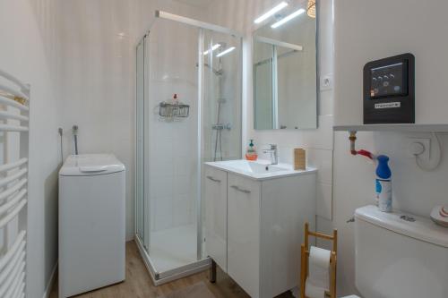 une salle de bain blanche avec une douche et un lavabo dans l'établissement Le petit Romo - Entre châteaux et Beauval, à Romorantin-Lanthenay