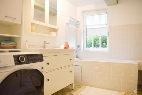 La salle de bains blanche est pourvue d'une baignoire et d'un lave-linge. dans l'établissement La Chaumière du Vallon -Piscine- Pont-l'Évêque 8P, à Vieux-Bourg