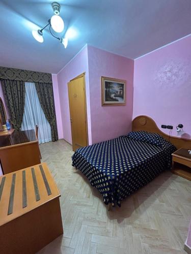 a bedroom with a bed in a room with pink walls at Hotel Canada in Falerna Marina