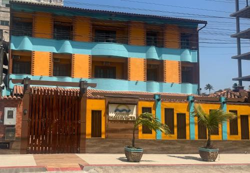a yellow and blue building with palm trees in front of it at Pousada Maravista in Anchieta
