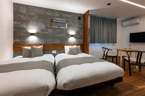 a hotel room with two beds and a table at SAUNA VILLA 然 in Nagano