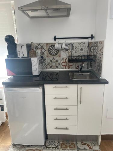 a small kitchen with white cabinets and a sink at La casuca de Candela in Santillana del Mar