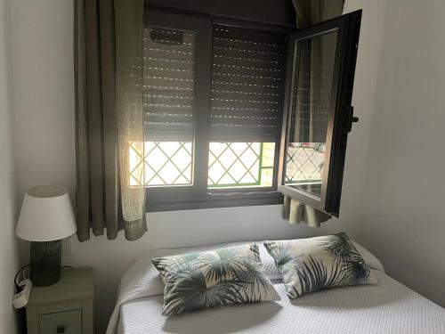 a bed with two pillows in front of a window at Luis Montoto in Seville