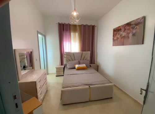 a small bedroom with two beds and a mirror at Appartement cosy à 5 min de la plage Sidi Kacem in Hajreien