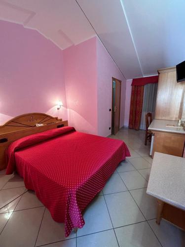 a bedroom with a red bed in a pink room at Hotel Canada in Falerna Marina