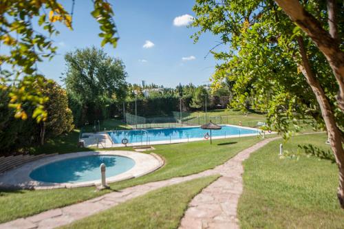 a swimming pool in a park with a tree at elegante apartamento con parking y gym en urbanización de Lujo en Aravaca in Madrid