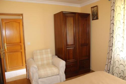 a bedroom with a bed and a chair and a cabinet at Maison individuelle in Ossun
