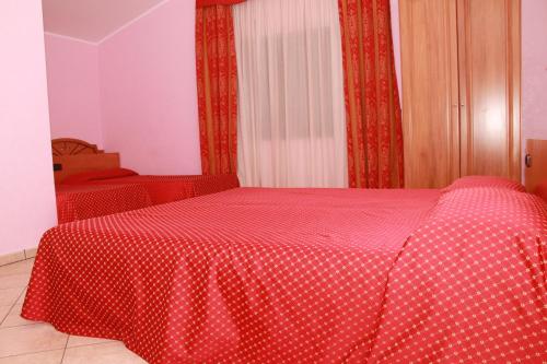 a red bed with a red and white polka dot blanket at Hotel Canada in Falerna Marina