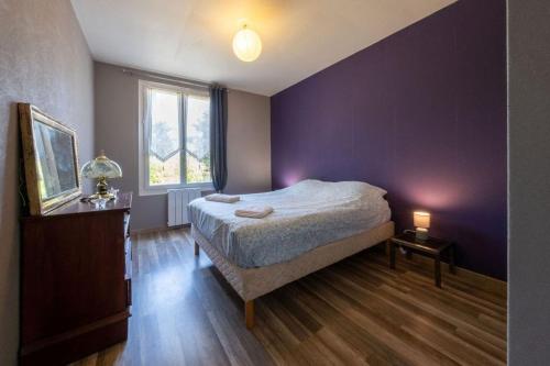Un dormitorio con una cama y una pared morada. en La Raboliote -Maison 3 chambres- jardin - 15 min Parc Fédéral Lamotte - CAUTION OBLIGATOIRE, en Brinon-sur-Sauldre