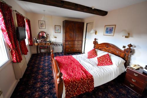 a bedroom with a large bed with a red blanket at The Greyhound Coaching Inn in Lutterworth