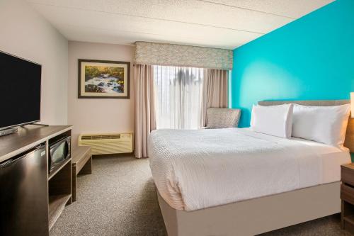 a hotel room with a bed and a flat screen tv at Days Inn by Wyndham Sudbury & Conference Centre in Sudbury