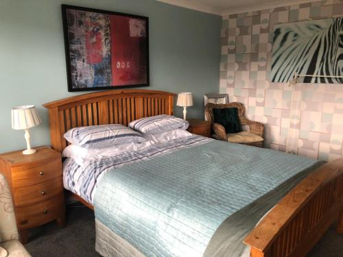 ein Schlafzimmer mit einem großen Bett und einem Stuhl in der Unterkunft Victorian Flat in Bonhill