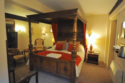 a bedroom with a wooden canopy bed with red pillows at The Greyhound Coaching Inn in Lutterworth