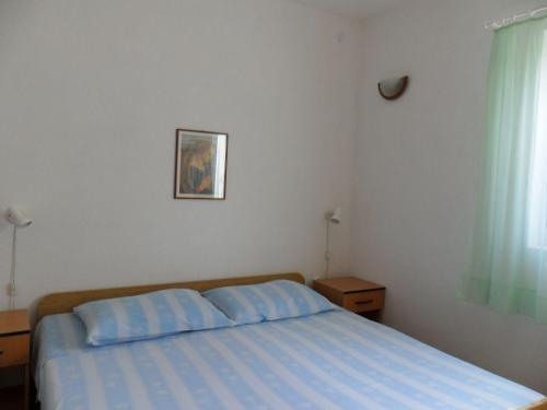 a bedroom with a bed with a blue comforter and a window at Apartments Gor in Sevid