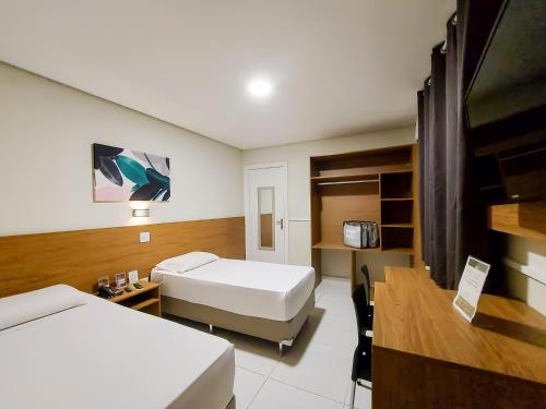 a hotel room with two beds and a desk at Hotel Itamarati Centro-República in Sao Paulo