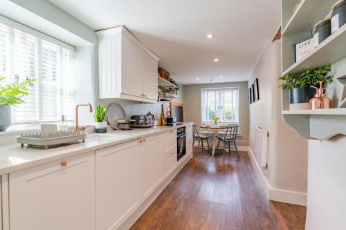 a kitchen with white cabinets and a table at Gable Cottage in Meysey Hampton