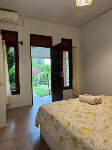 a bedroom with a bed and a door to a yard at Alam Kowang Villa in Tejakula