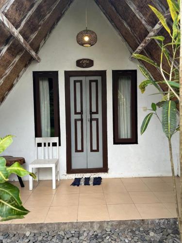 a front door of a white house with a chair at Alam Kowang Villa in Tejakula