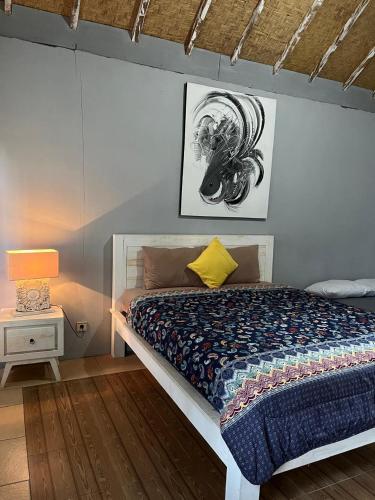 a bedroom with a bed and a lamp on a table at Alam Kowang Villa in Tejakula