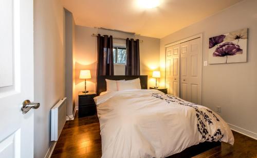 a bedroom with a white bed and two lamps at Royal Laurentien in Mont-Blanc