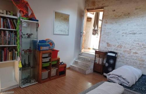 a living room with a book shelf and a window at Les chambres du Nid charentais in La Poterie