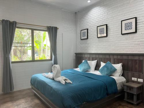 a bedroom with a bed with blue sheets and a window at Villas Chalitaa วิลล่าชาลิตา in Chiang Mai