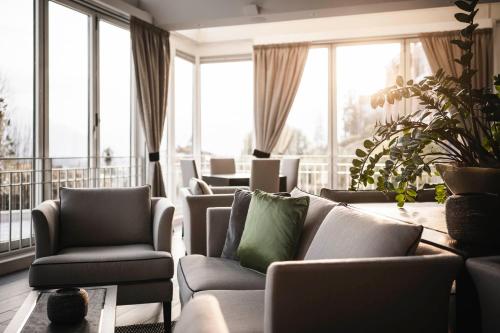 a living room with couches and chairs and windows at Hotel Belvedere Locarno in Locarno