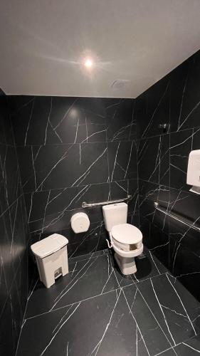 a bathroom with two toilets and a black tiled wall at Flat Premium Legacy Suites - Cabo Branco in João Pessoa