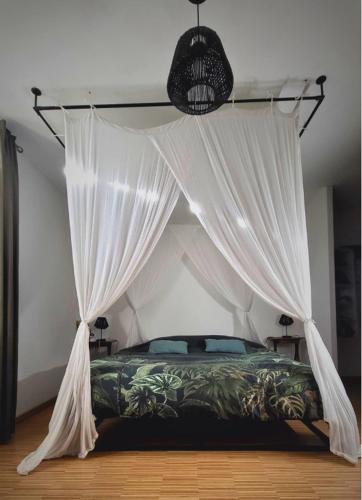 a bedroom with a canopy bed with white curtains at Les chambres du Nid charentais in La Poterie