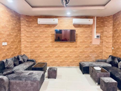 a living room with couches and a tv on a brick wall at Lamoon Villa in Hat Yai