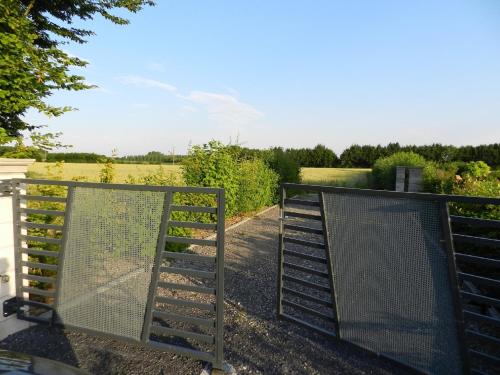 a pair of gates with a field in the background at Gîte La Grenouillère in Esquéhéries