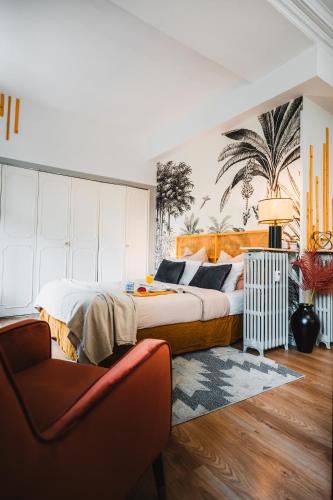 une chambre avec un grand lit et une chaise dans l'établissement RoomChic - Les Ambassadeurs, à Vichy