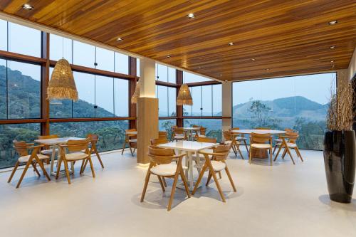 a restaurant with tables and chairs and large windows at Pousada A Rosa e o Rei in São Francisco Xavier