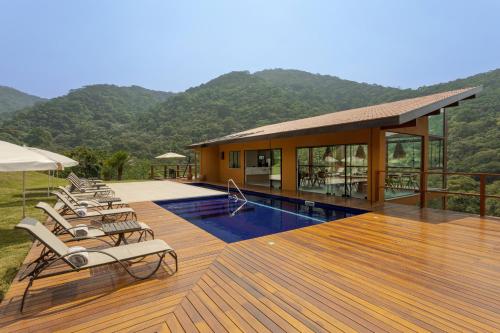 a deck with chairs and a pool and a building at Pousada A Rosa e o Rei in São Francisco Xavier
