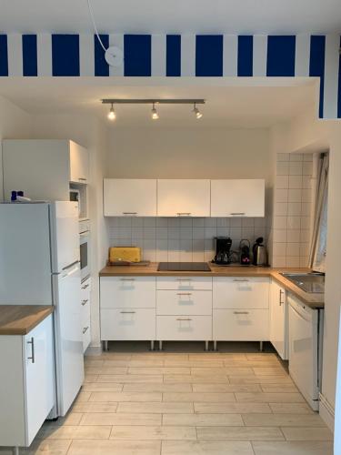 une cuisine avec des armoires blanches et des appareils bleus et blancs dans l'établissement Appartement - bord de mer - Le Touquet - WIFI, à Le Touquet-Paris-Plage