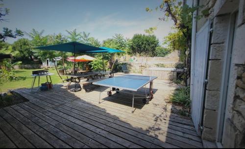 a ping pong table and umbrella on a deck at Les chambres du Nid charentais in La Poterie