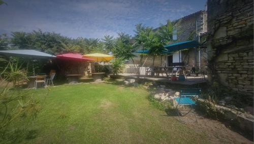 a yard with chairs and umbrellas and a building at Les chambres du Nid charentais in La Poterie